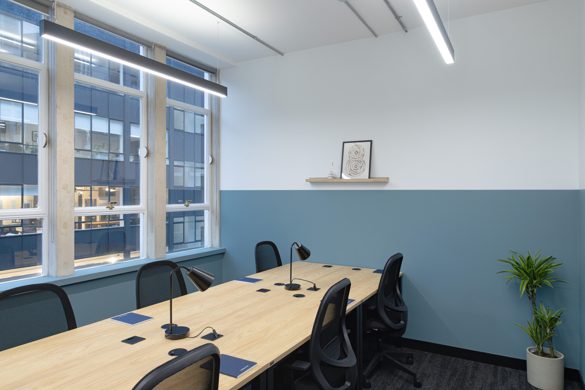 Work.Life Courtyard Building private workspace with blue walls, black office chairs and a large desk. Bespoke and personalised Work.Life notepads sit on all the spaces.