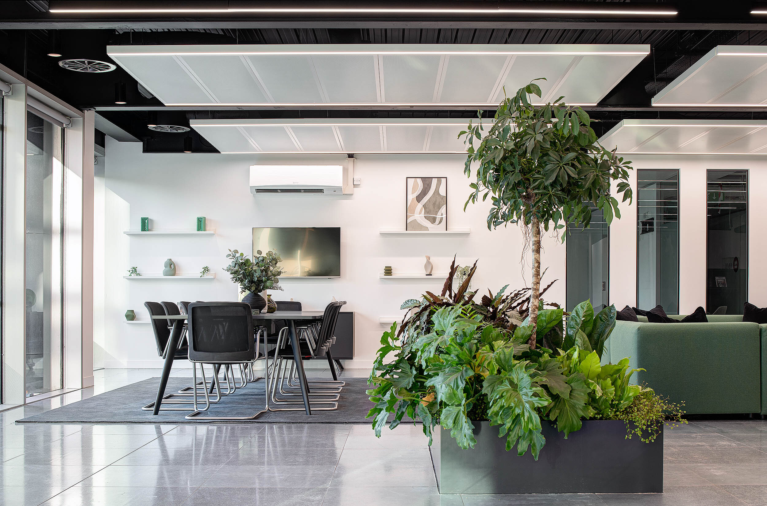 Modern office interior designed by Two, featuring a meeting area, biophilic planter, and minimalist decor.