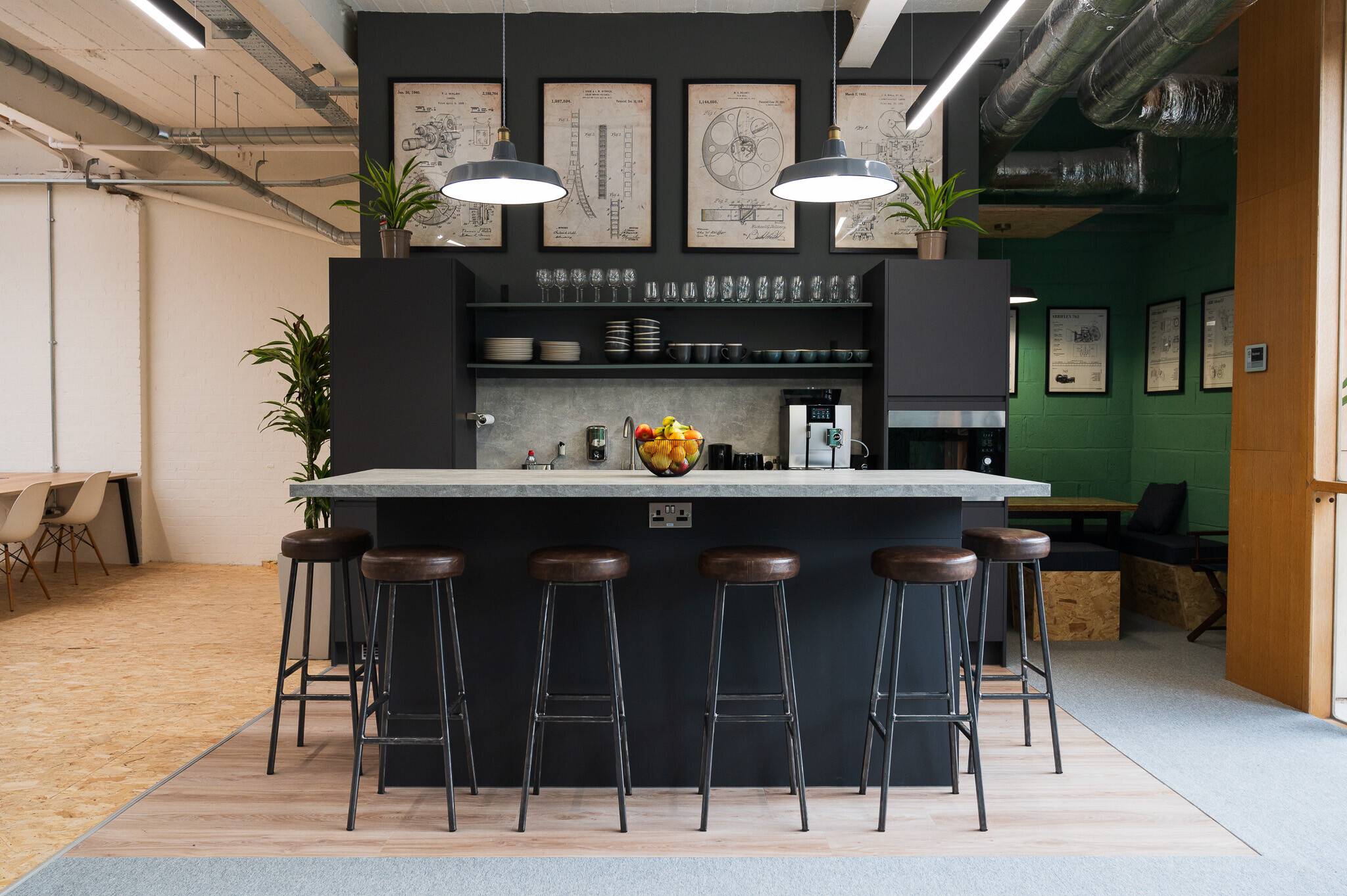 Industrial-style teapoint in the FOMO Rentals office, designed by Two, with high stools, hanging pendant lights, and a modern black counter.