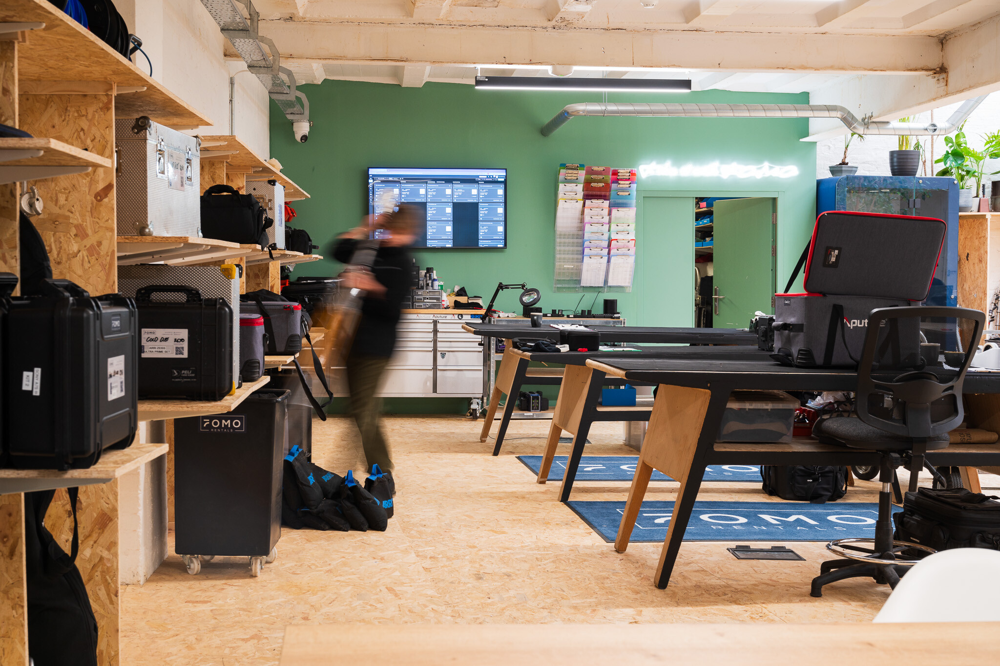 A sleek and functional equipment storage area in the FOMO Rentals office, featuring built-in shelving and organised workstations.