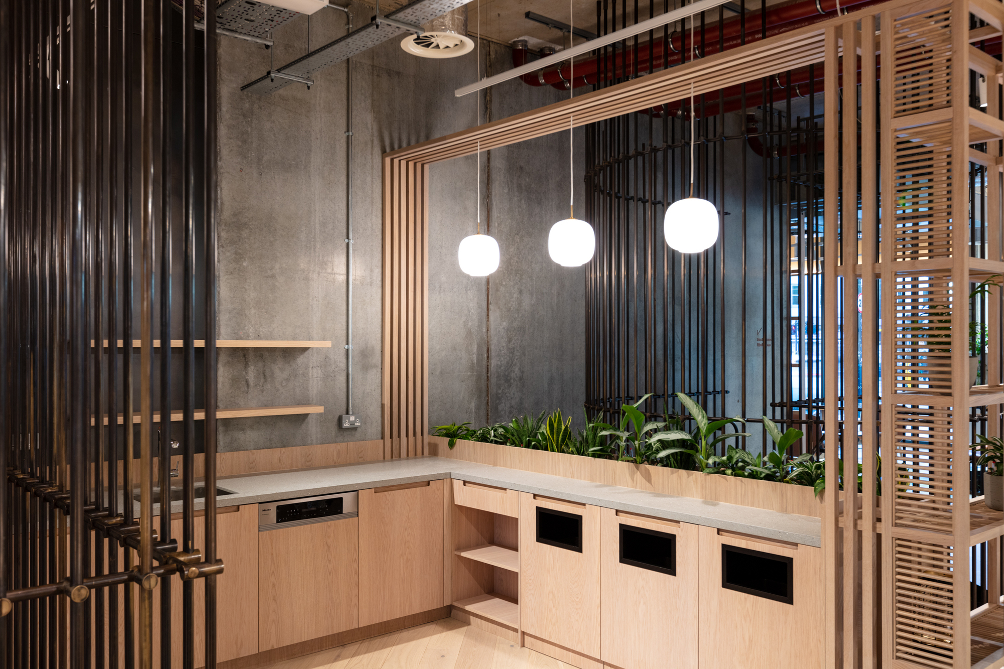 Minimalist teapoint with pendant lighting, wooden finishes, and integrated greenery at the FORA Borough Market coworking space, designed by Two.
