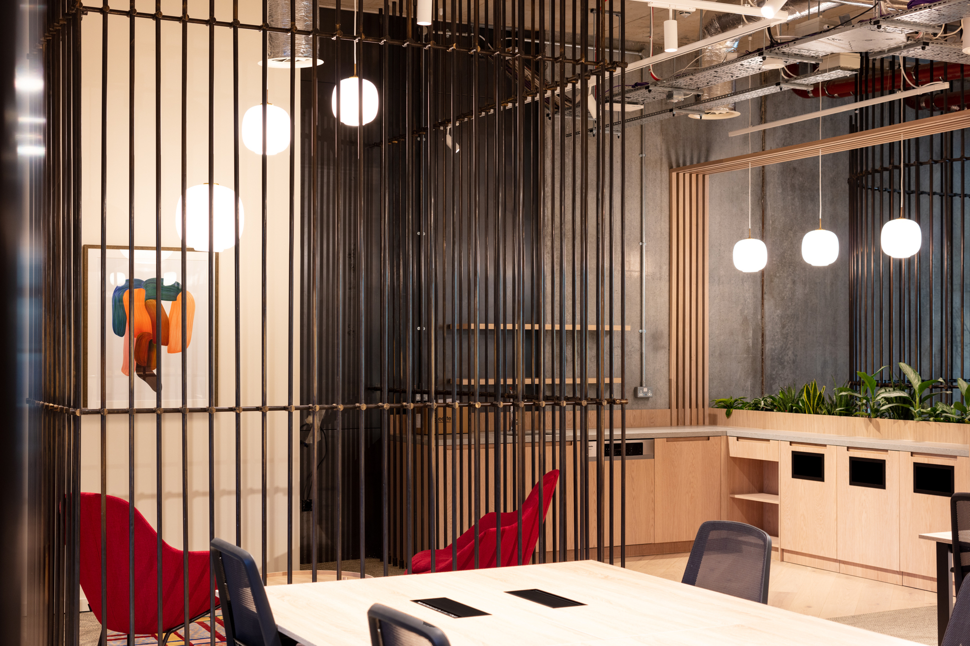 Modern office design featuring black vertical bars, vibrant red seating, and pendant lighting at FORA Borough Market, crafted by Two