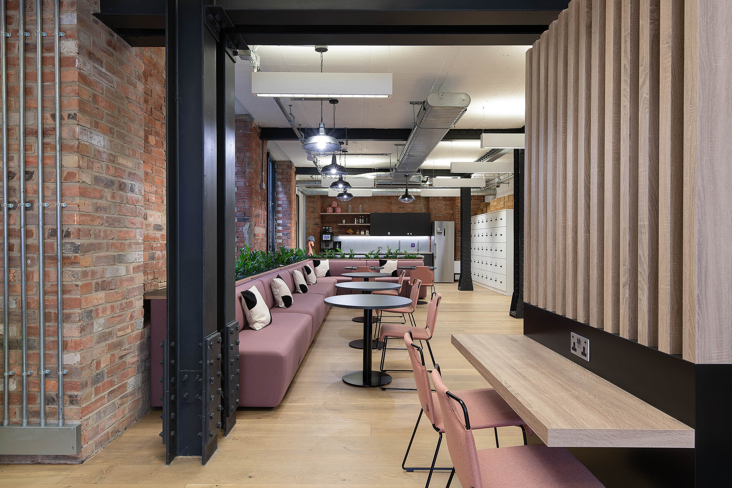 Collaborative workspace designed by Two, showcasing stylish seating, exposed brick interiors, and a communal workstation.