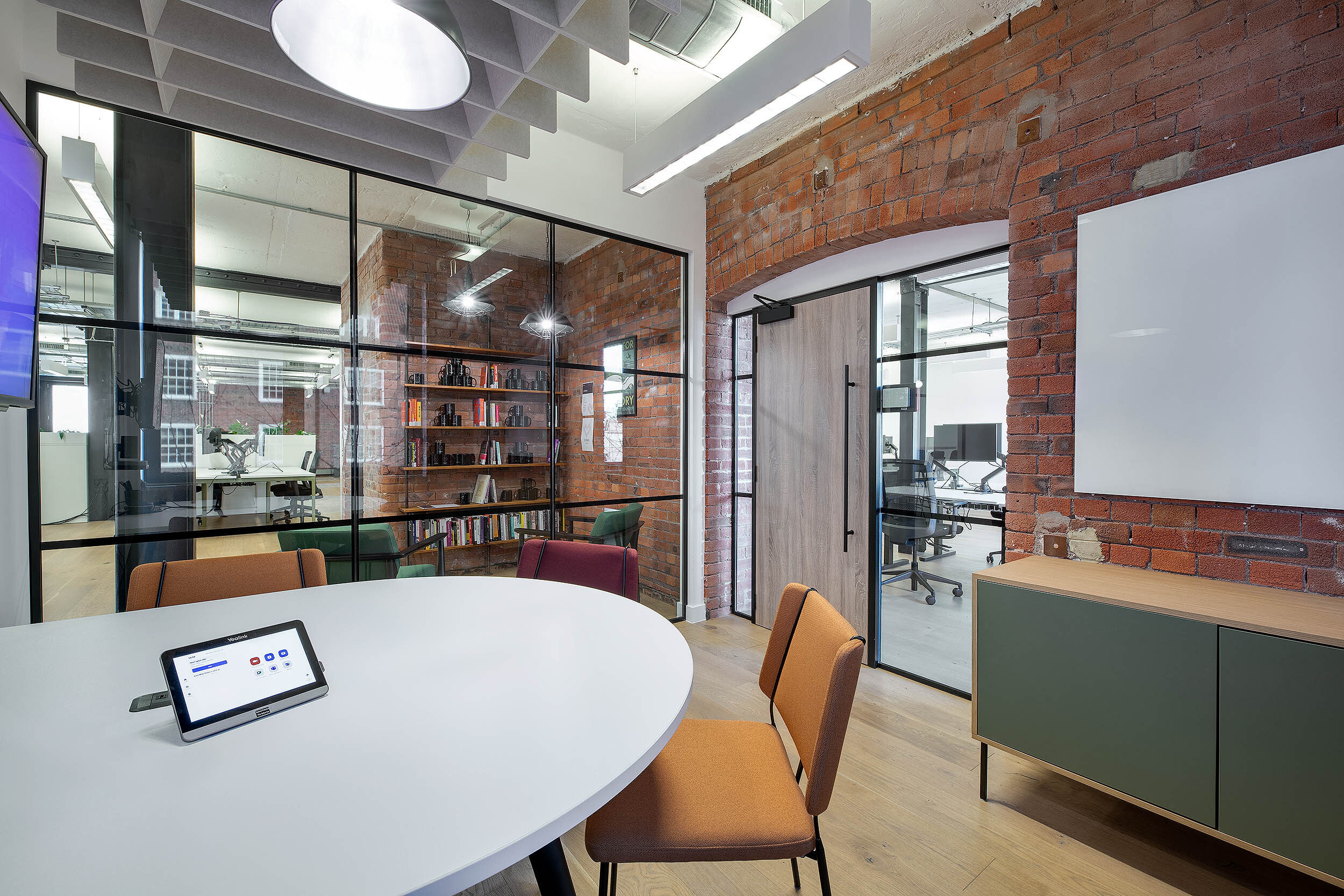 Private meeting room in the Kin & Carta office, designed by Two, featuring glass partitions, warm wood tones, and comfortable furnishings.