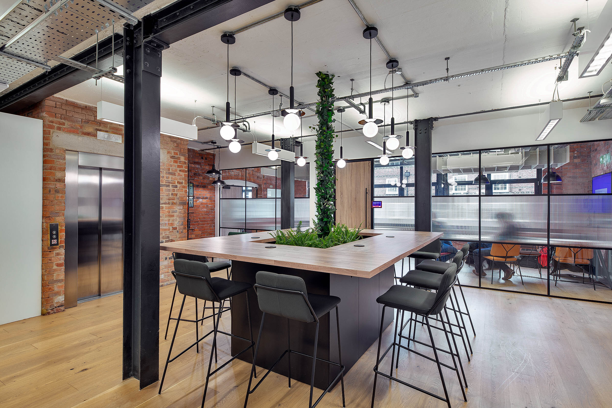 Creative workspace at the Kin & Carta office by Two, featuring an open-plan layout with greenery and a central collaboration island.