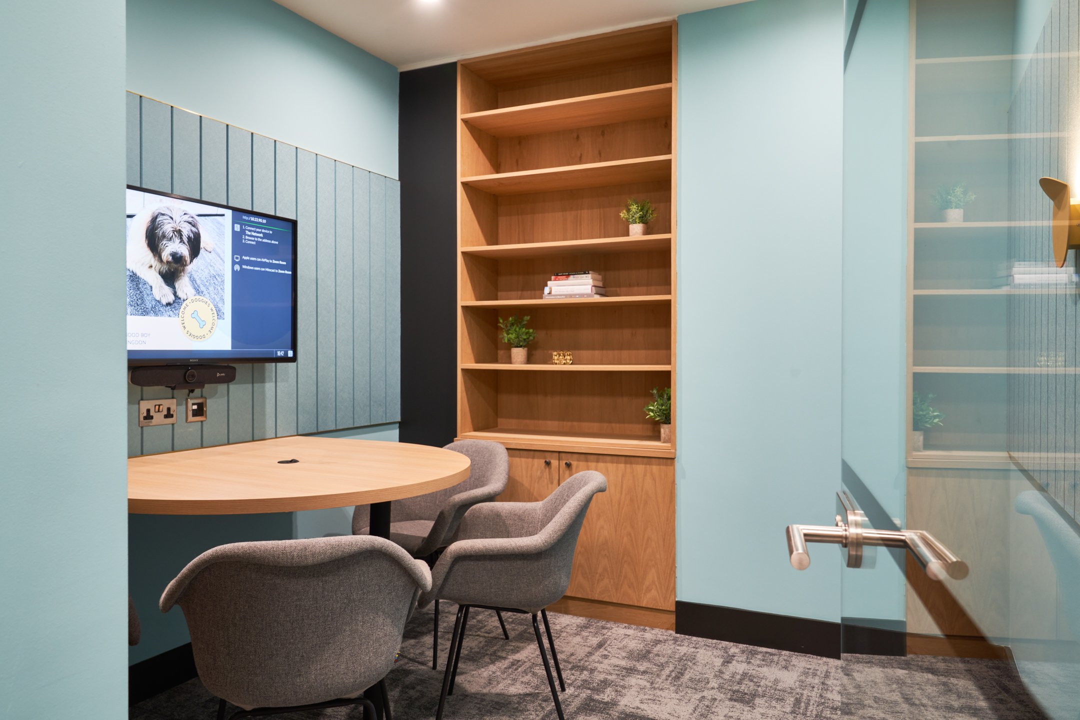 A private meeting room at Work.life Liverpool Street by Two, showcasing soft blue walls, bespoke shelving, and a round table setup, perfect for focused discussions in a modern workspace.