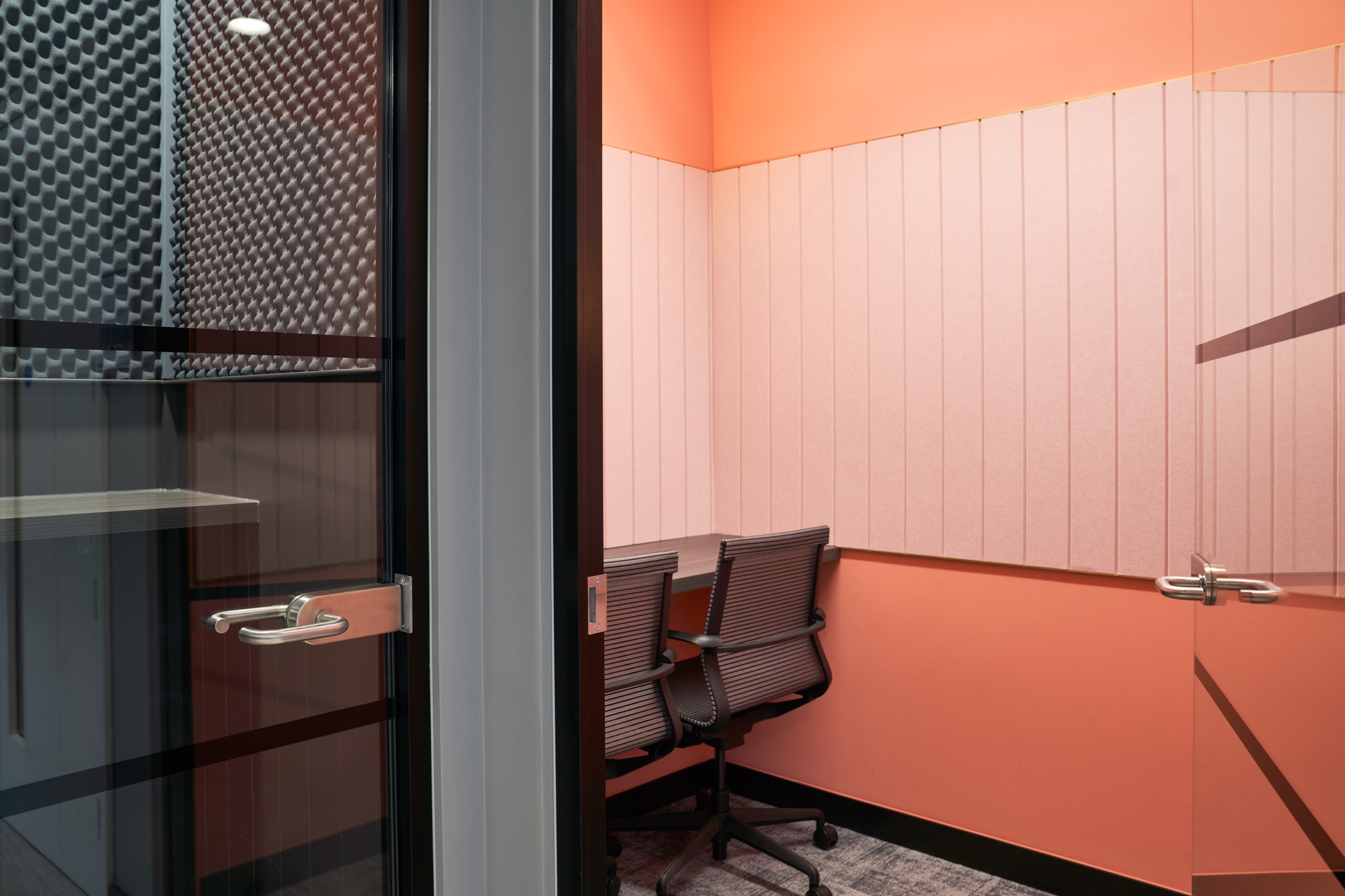A cosy phone booth at Work.life Rivington House, with soundproofed walls and a bright orange design, providing a private workspace option by Two.