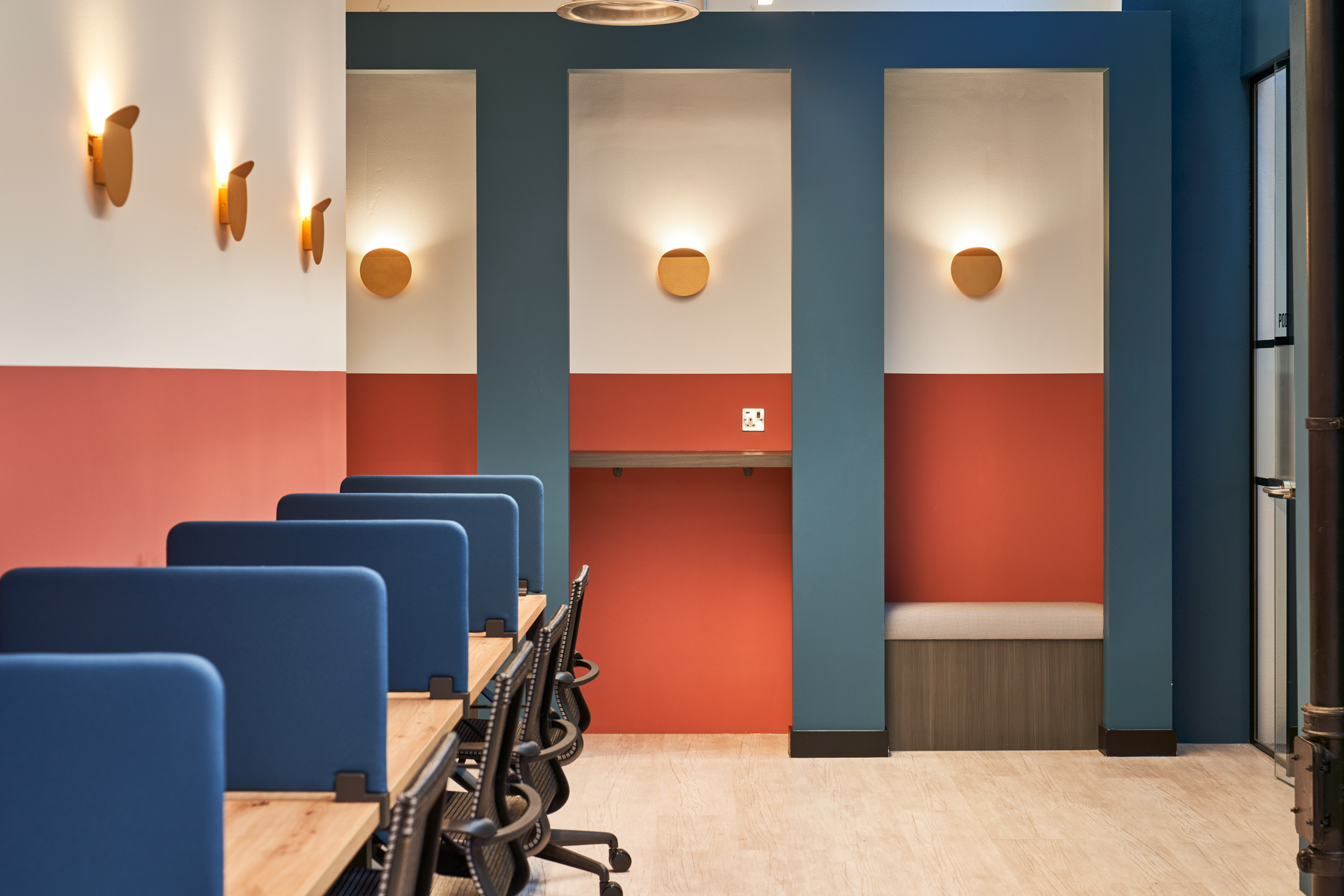 Dedicated desk space at Work.life Rivington House, with comfortable chairs, blue privacy panels, and bold colour accents, offering a productive workspace designed by Two.