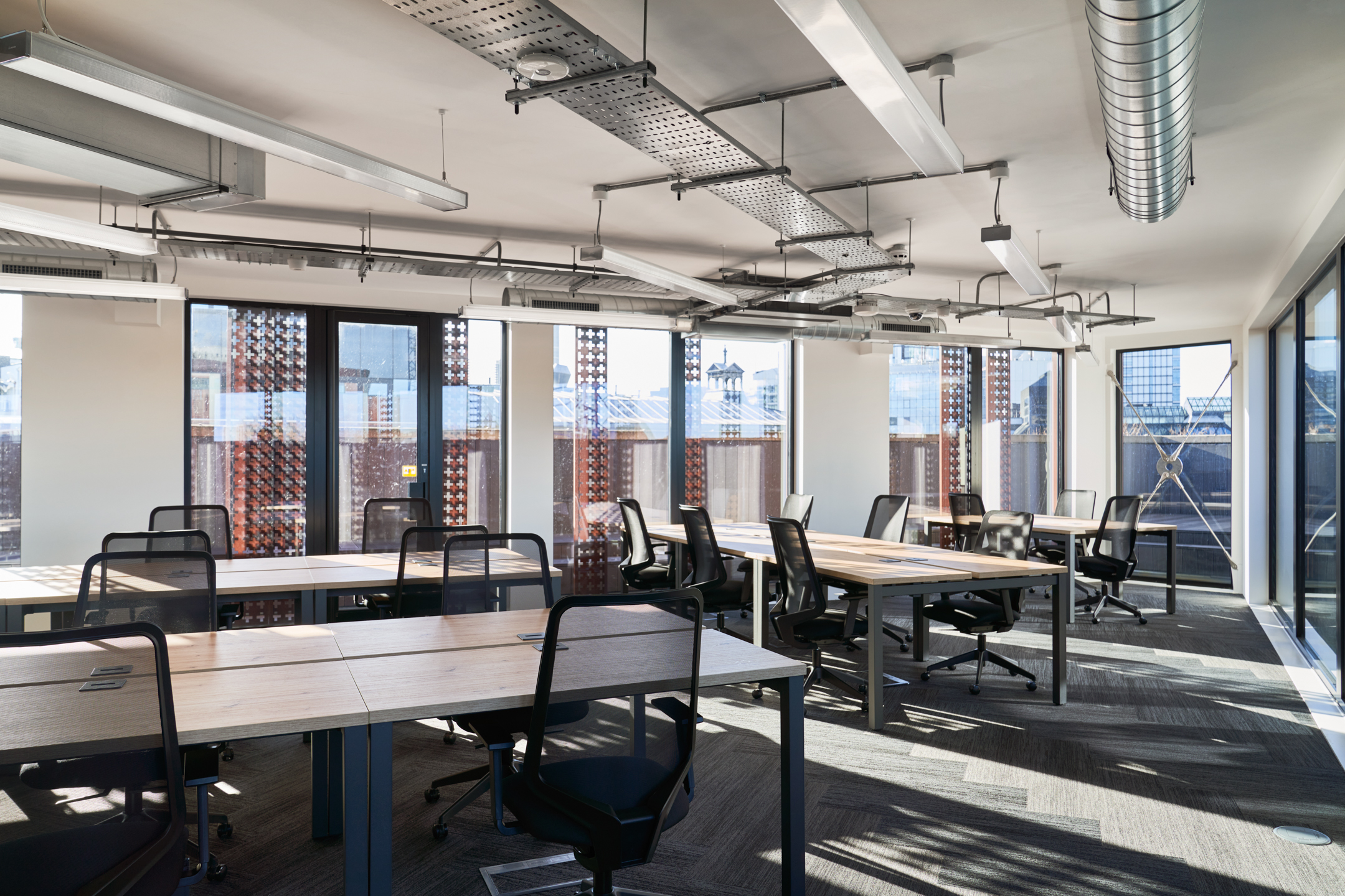 A bright and spacious open-plan office at Work.life Rivington House, designed by Two, with natural wood desks and expansive windows providing a productive and inspiring workspace.