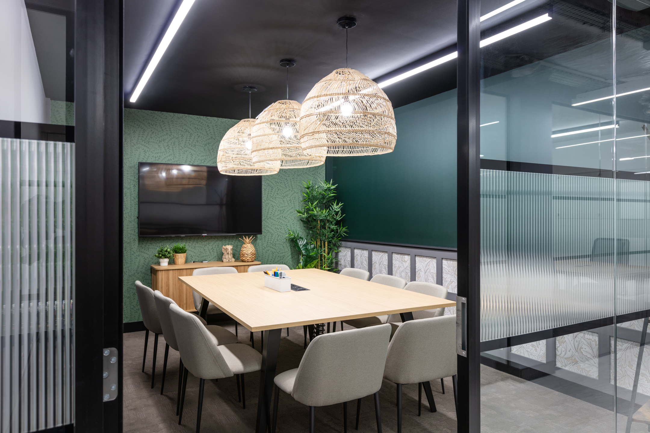 A private meeting room at Work.life Red Lion Street, with wicker lighting, a green accent wall, and thoughtful design elements by Two for seamless workspace functionality.