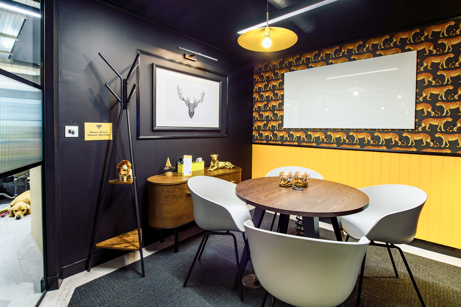 A meeting room at Work.life Soho by Two, featuring a warm palette, unique leopard-pattern wallpaper, and workspace essentials like a whiteboard and seating.