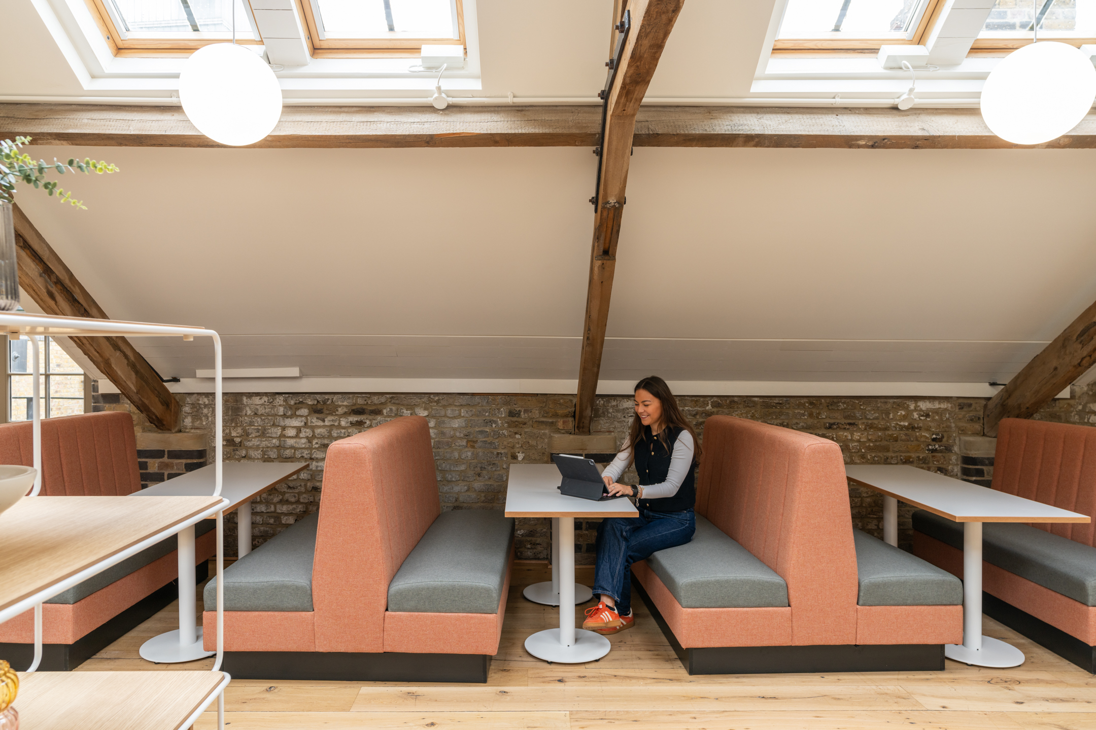 The Varnish Works seating quiet area featuring pink benches, white desking and hanging bulb lights