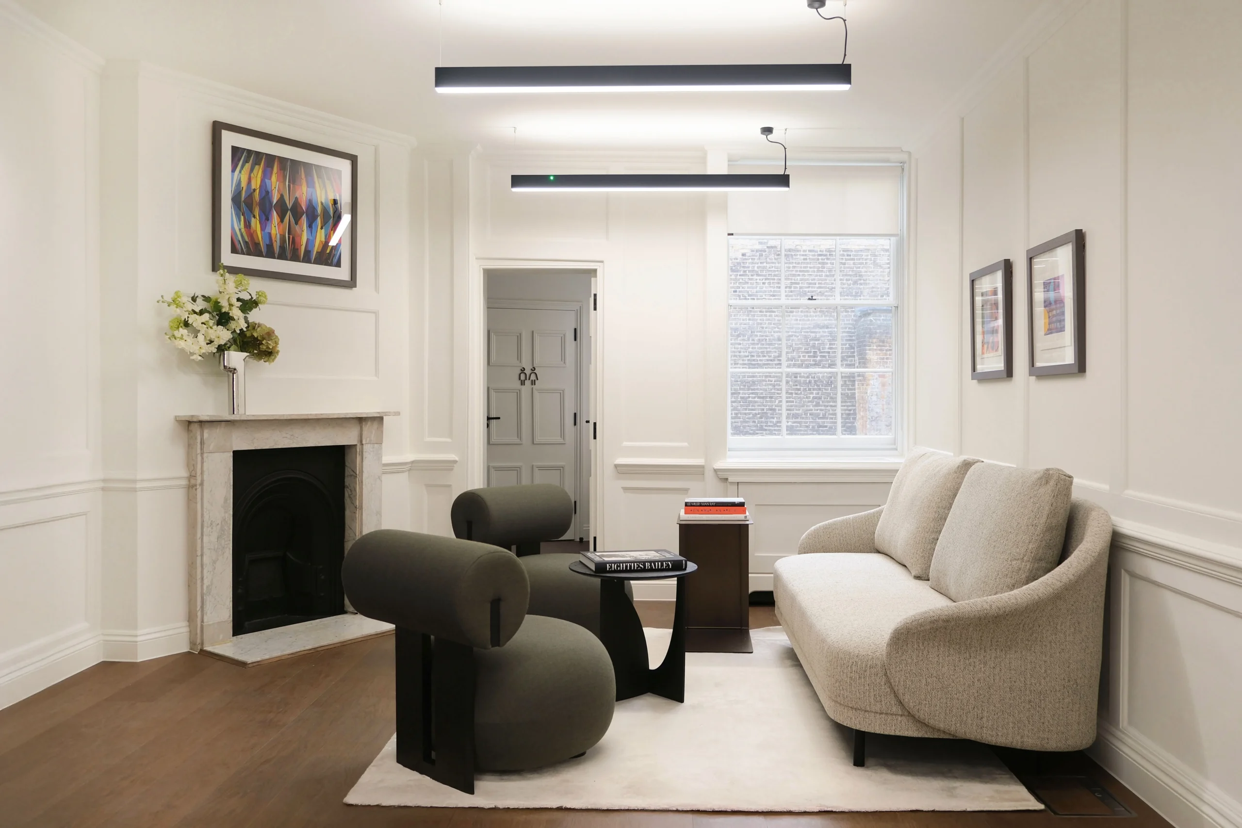 33 Mayfair elegant seating area with soft grey furnishing, hanging art and overhead lighting.